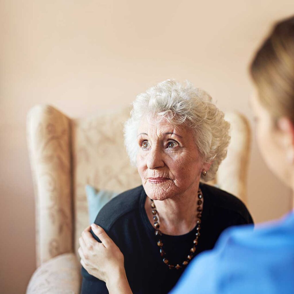 Older resident speaking with a family member in a comfortable assisted living lounge.